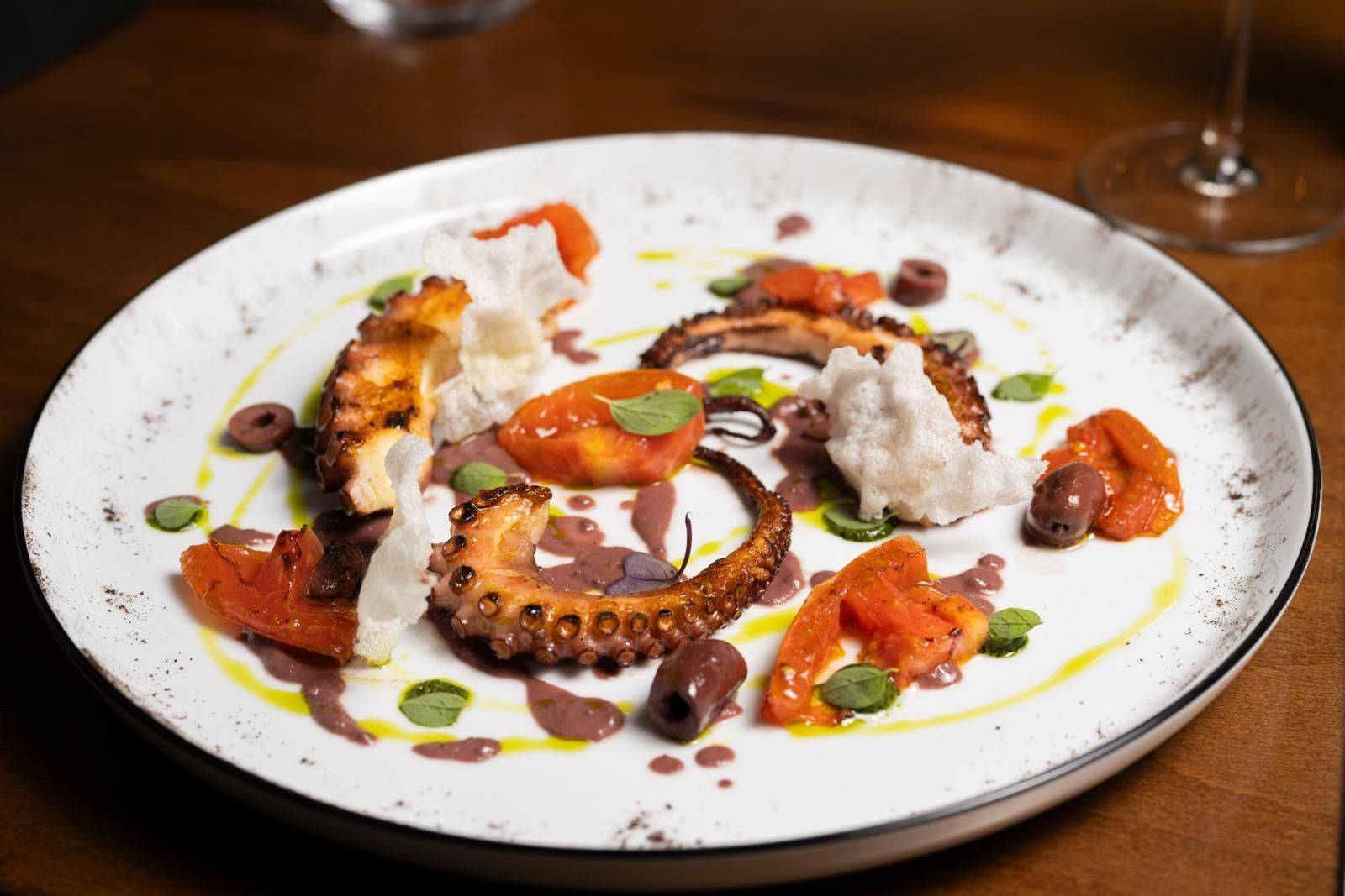 Gegrillter Oktopus, angerichtet mit Gemüse und Saucen