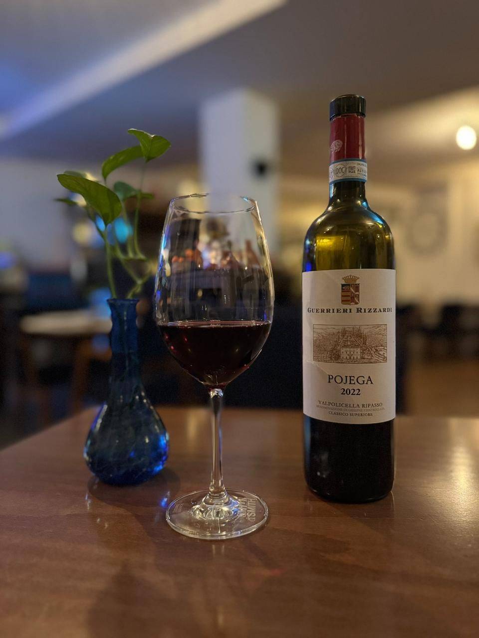 Rotwein und eine blaue Vase auf einem Holztisch